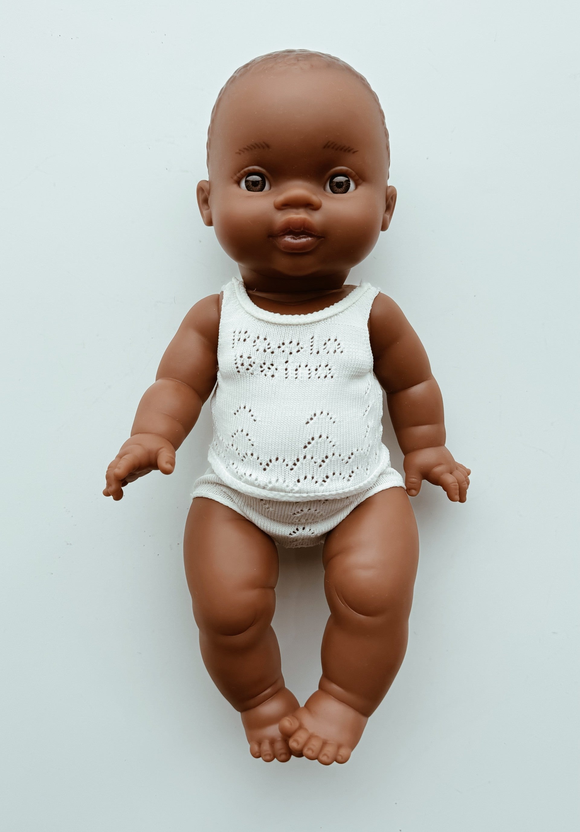 Baby doll with a white outfit on a light gray background